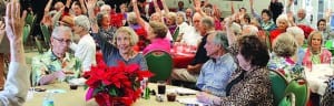Pinecrest Pioneers residents over 90 years old raise their hands during December luncheon.