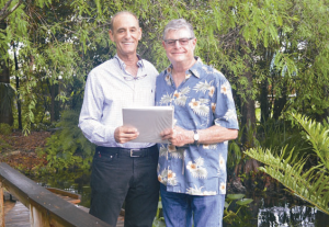 Garden Club president Richard Dorn (right) is pictured presenting the award documents to Dr. Lloyd Wruble in his garden.